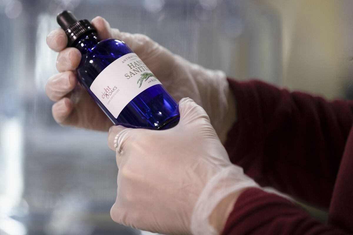 Carly Snyder caps a bottle of hand sanitizer made at the Eight Oaks Farm Distillery in New Tripoli, Pa., Monday, March 16, 2020. The distillery's owner, Chad Butters, grew increasingly angry as he saw the skyrocketing price of hand sanitizer. So he's temporarily converting his operation into a production line for the suddenly hard-to-find, gooey, alcohol-based disinfectant. (AP Photo/Matt Rourke)