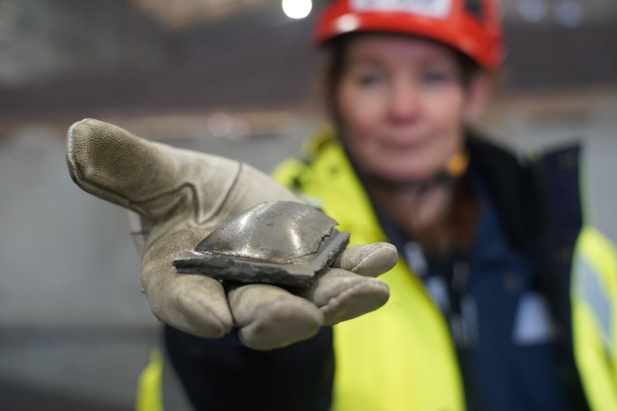 Susanne Rostmark, research leader, LKAB, holds a piece of hot briquetted iron ore made using the HYBRIT process nearby the venture’s pilot plant in Lulea, Sweden on Feb. 17, 2022. The steel-making industry is coming under increasing pressure to curb its environmental impact and contribute to the Paris climate accord, which aims to cap global warming at 1.5 degrees Celsius (James Brooks via AP)