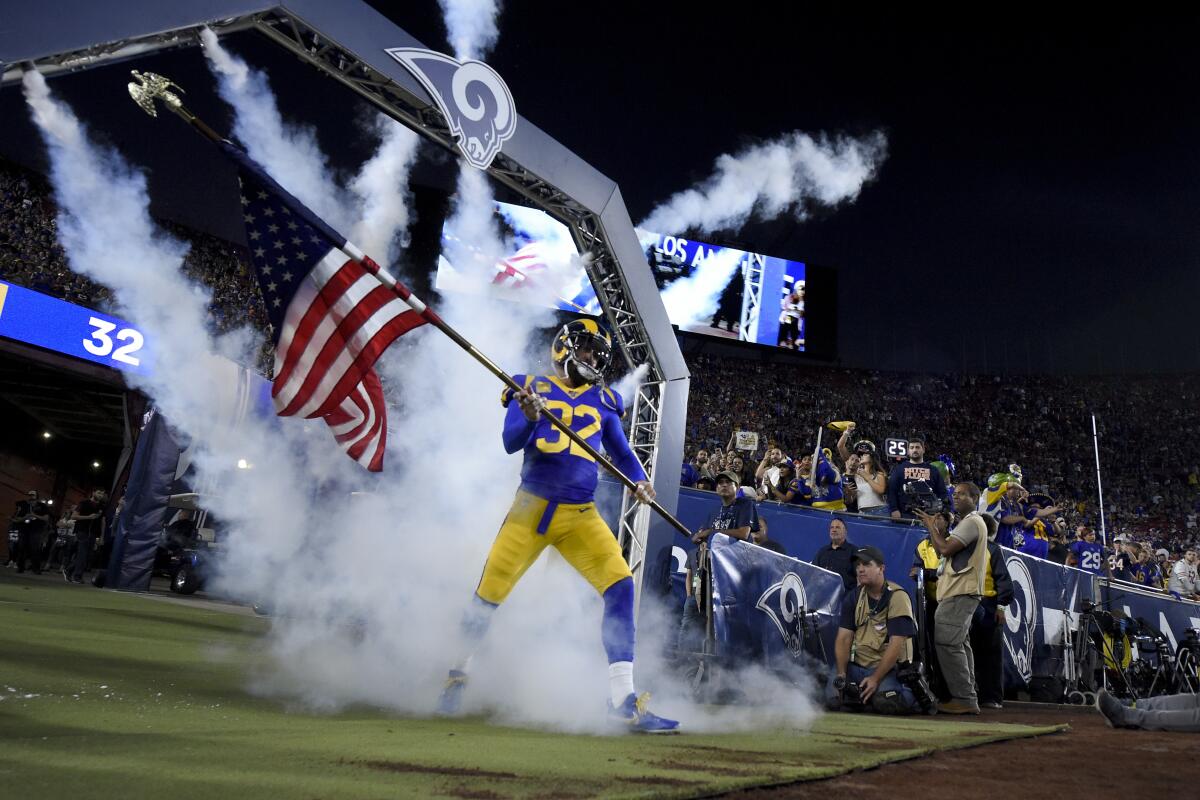 The Rams' Eric Weddle walks onto the field with a U.S. flag