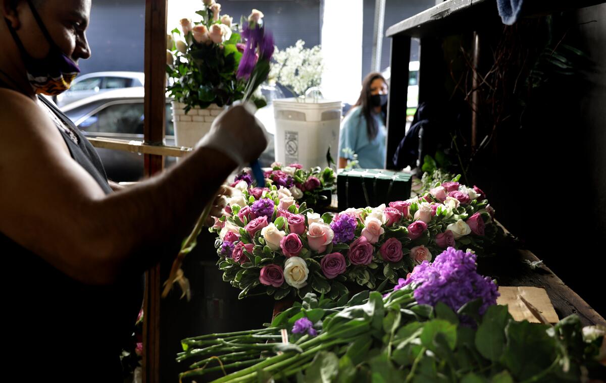 Jaime Miranda creates an arrangement at Lupita's Flowers in downtown Los Angeles on Wednesday. Flower wholesalers have already been allowed to reopen and other select retailers can open Friday.