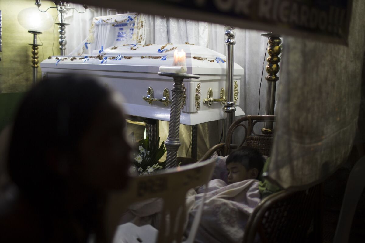 Children of a Ricardo de Lemon, 36, who was killed, sleep beside the coffin during a wake in Manila.