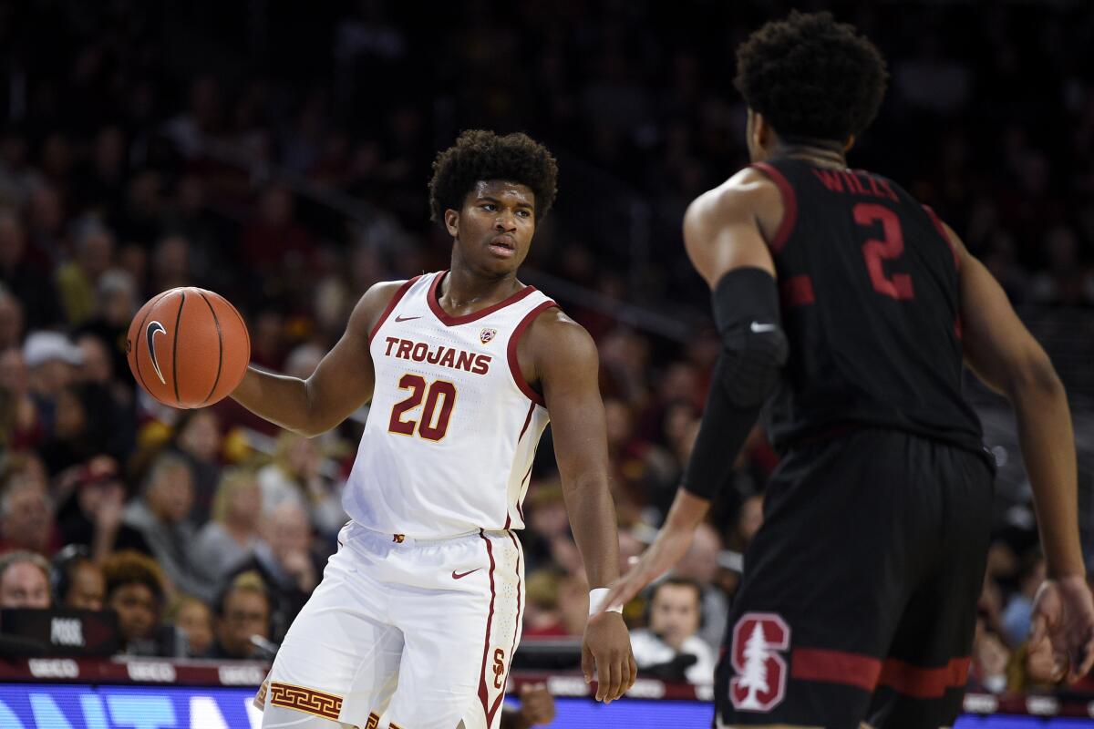 USC guard Ethan Anderson, left, handles the ball in front of Stanford guard Bryce Wills during the first half on Saturday at the Galen Center.