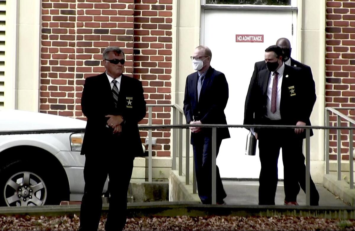 In this image from video, Travis McMichael, center, accused in the shooting death of Ahmaud Arbery, is led by security officers from the Glynn County Courthouse in Brunswick, Ga., Wednesday, May 12, 2021. A Georgia judge will continue hearing legal motions Thursday in the murder case of three men facing a fall trial in the slaying of Ahmaud Arbery, a Black man who was chased and shot after being spotted running in the defendants' neighborhood. (AP Photo/Lewis M. Levine)