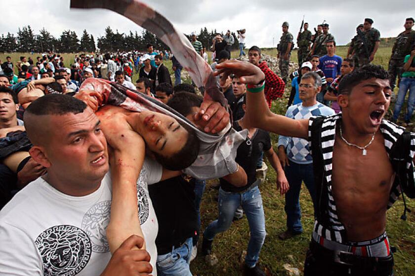 Protesters in Lebanon carry a Palestinian boy said to be injured when Israeli soldiers opened fire at protesters who approached the border with Israel during a rally in the village of Maroun el-Ras. Israeli border clashes kill 15 on Palestinian protest day