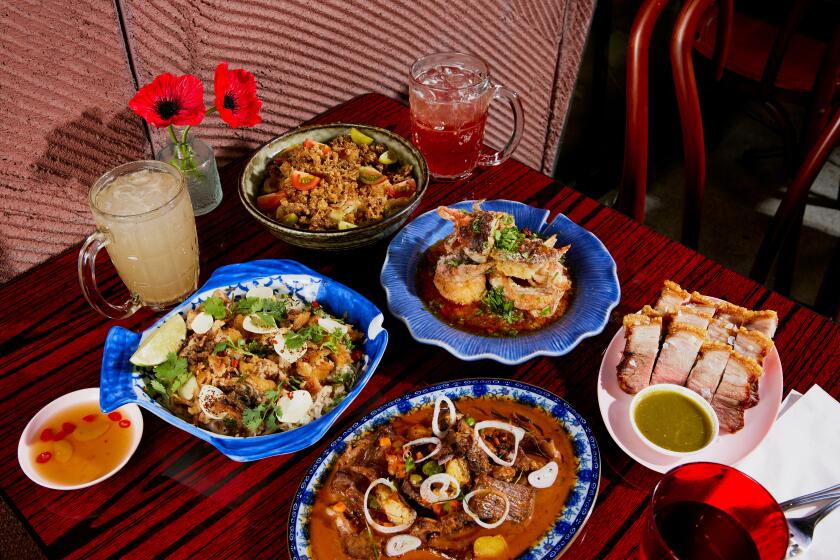 LOS ANGELES, CA - AUGUST 7, 2024: A feast of Holy Basil's signature dishes, including (clockwise from top) Papaya Salad, Soft Shell Crab with Salted Yolk, Moo Krob, Penang Short Rib, and Grandma's Fish and Rice. (Jennelle Fong / For The Times)