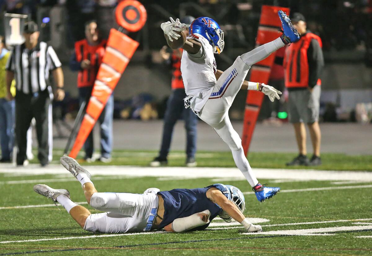Corona del Mar’s Mason Gecowets trips up Los Alamitos’ Oscar Brown V in a Sunset League game at Davidson Field on on Nov. 1 2019.