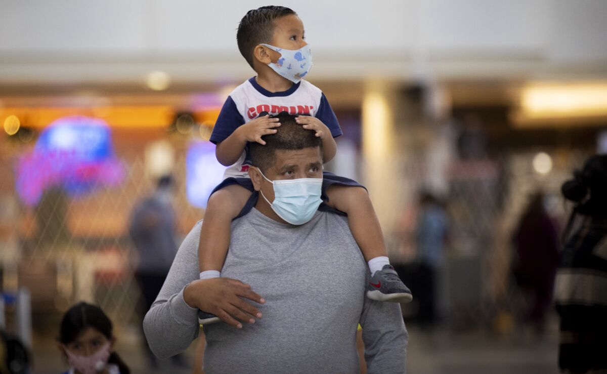 Mario Tejada carries his son Mario Tejada Jr., 3, on his shoulders at Los Angeles International Airport on Tuesday.
