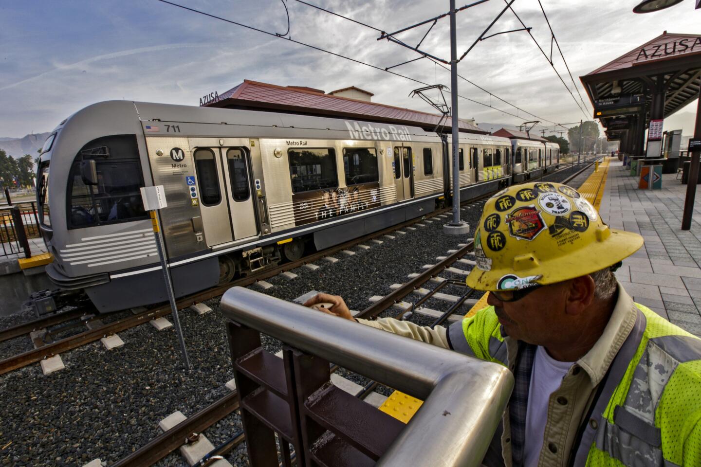 Lino Cabriales does a last-minute paint touch-up as a Metro Gold Line train leaves the new Azusa station on a test run. The 11.5-mile Foothill Extension, taking the Gold Line deeper into the San Gabriel Valley, opens Saturday.