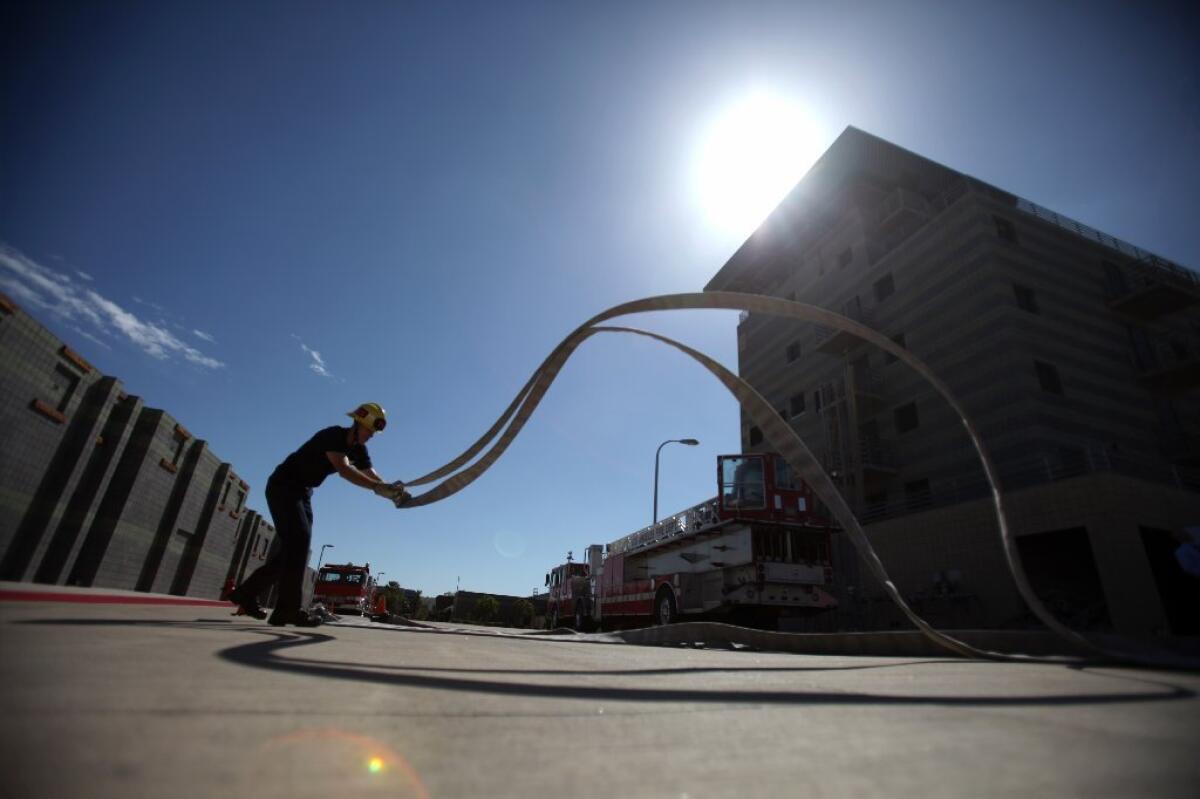 LAFD recruits at the drill tower in Panorama City hustle during a training exercise on laying out hoses in the proper fashion.