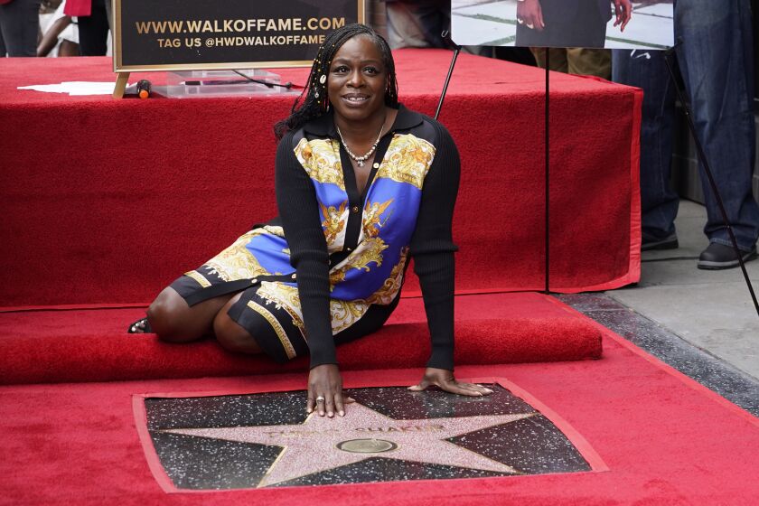 Sekyiwa "Set" Shakur poses atop her late brother rapper/actor Tupac Shakur's star on the Hollywood Walk of Fame during a posthumous ceremony in his honor on Wednesday, June 7, 2023, in Los Angeles. (AP Photo/Chris Pizzello)