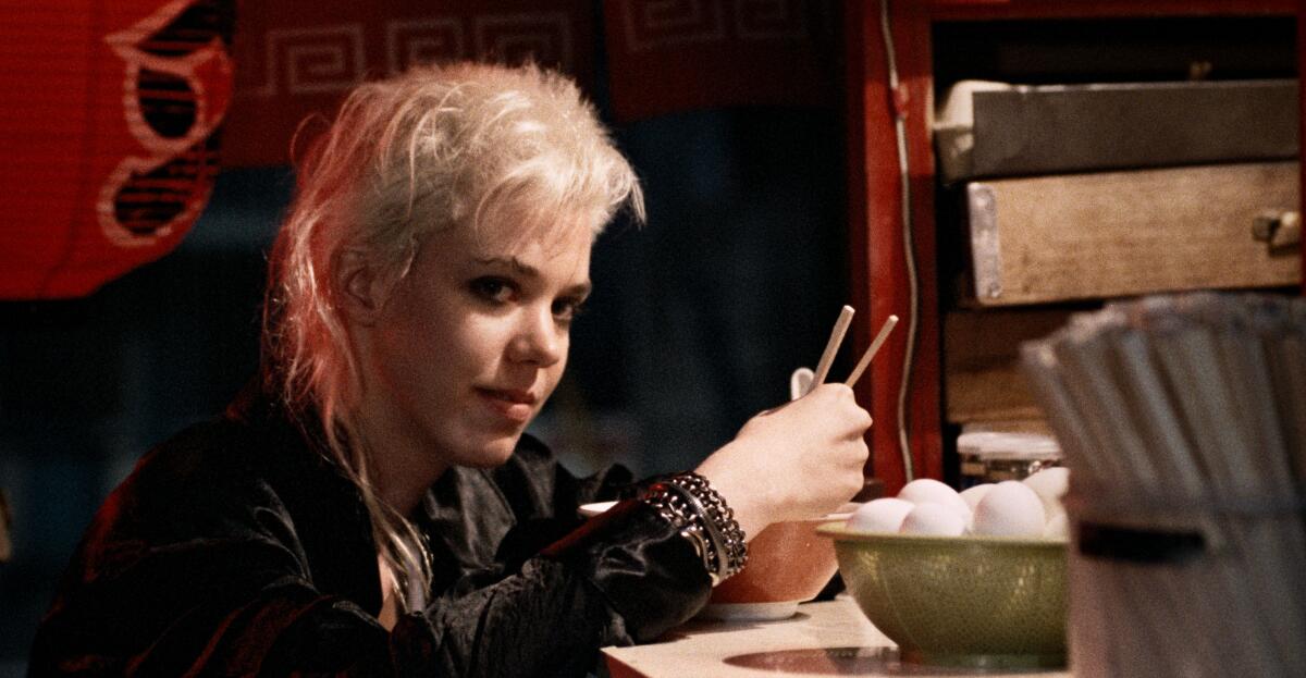 A bleach-blond, post-punk woman sits at a sushi bar.