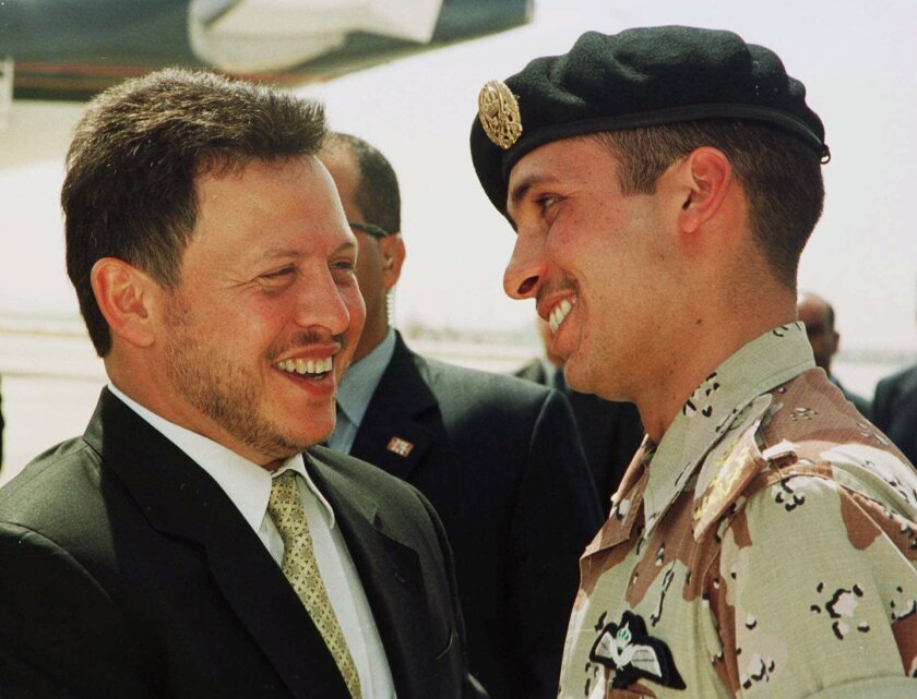 King Abdullah II and Prince Hamzah smile at each other on an airport tarmac.