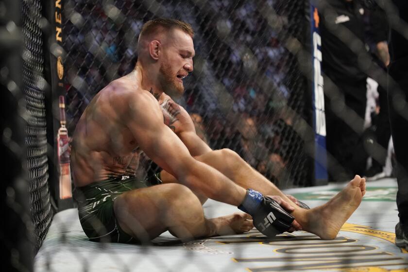 Conor McGregor holds his right ankle while fighting Dustin Poirier during a UFC 264 lightweight mixed martial arts bout Saturday, July 10, 2021, in Las Vegas. (AP Photo/John Locher)