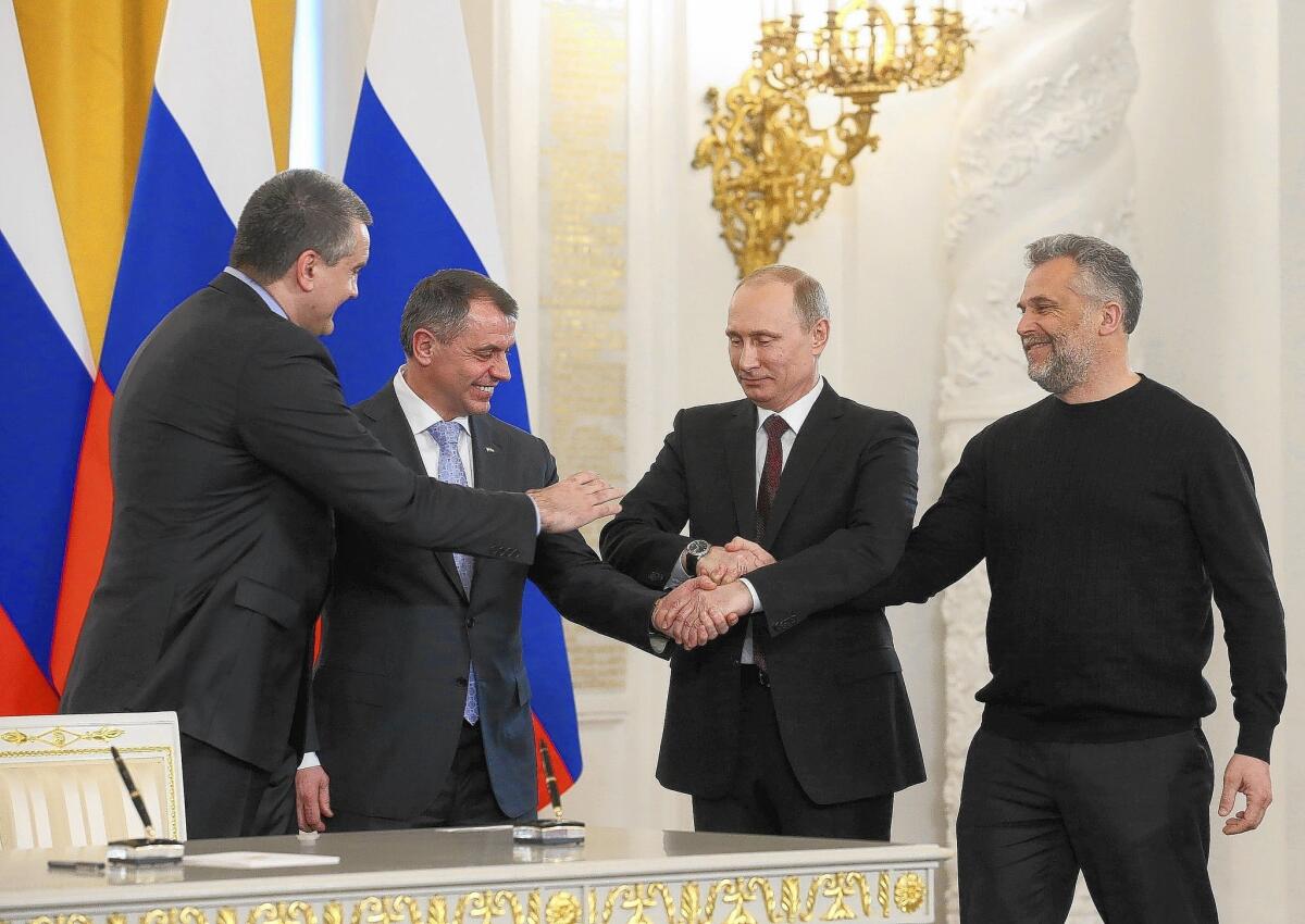 Russian President Vladimir Putin and three Crimean politicians are seen joining hands in Moscow on Tuesday after signing a treaty on the Ukrainian Black Sea peninsula becoming part of Russia.