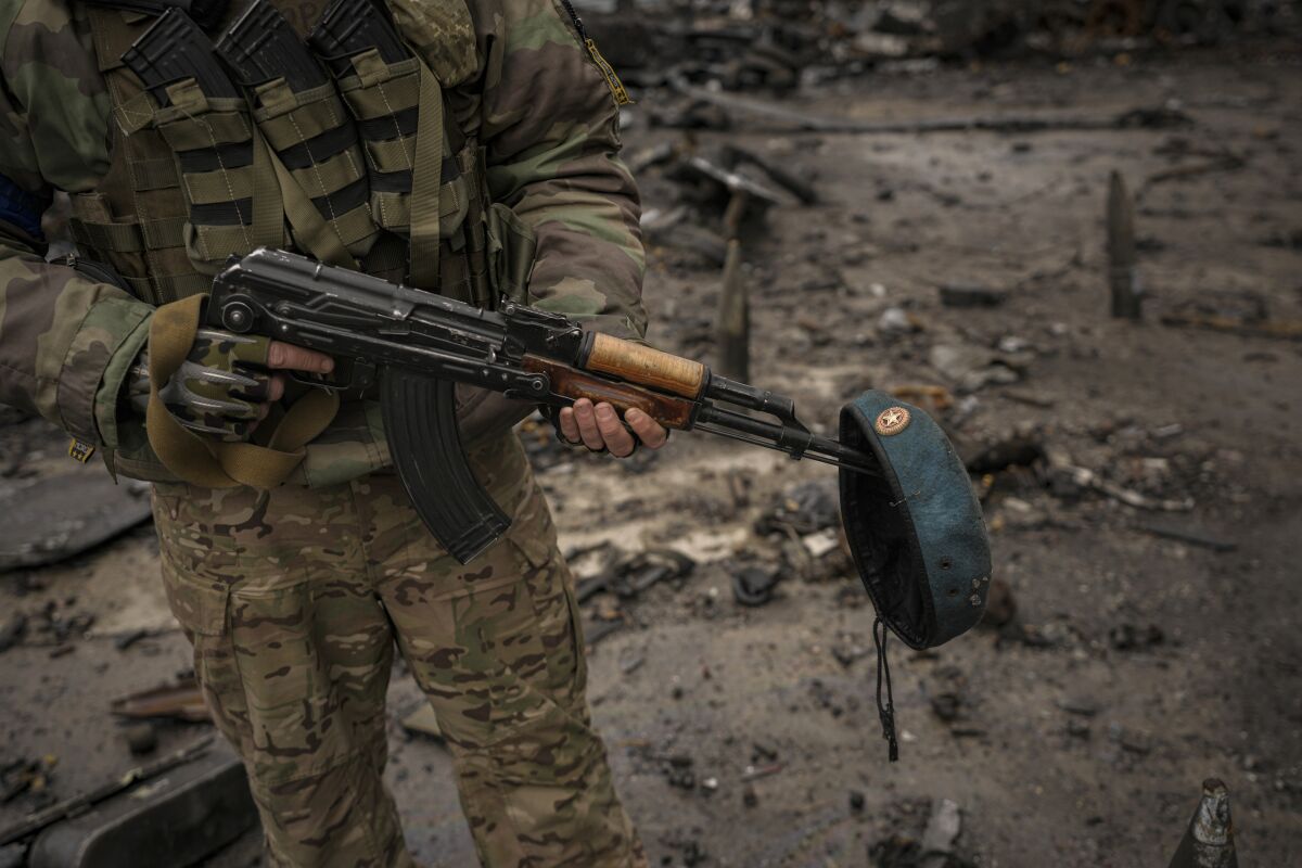 A Ukrainian serviceman with a Russian beret from destroyed Russian military vehicles on his weapon, at the Antonov airport 