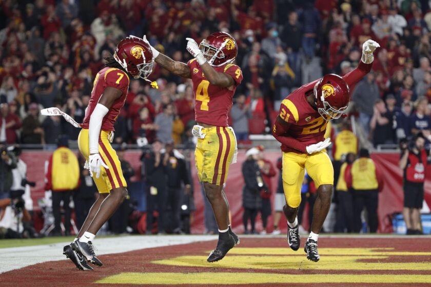 LOS ANGELES, CA - NOVEMBER 26, 2022: USC Trojans defensive back Calen Bullock (7) reacts with USC Trojans defensive back Max Williams (4) and USC Trojans defensive back Latrell McCutchin (21) after intercepting a pass late in the game against Notre Dame at the Coliseum on November 26, 2022 in Los Angeles, California.(Gina Ferazzi / Los Angeles Times)