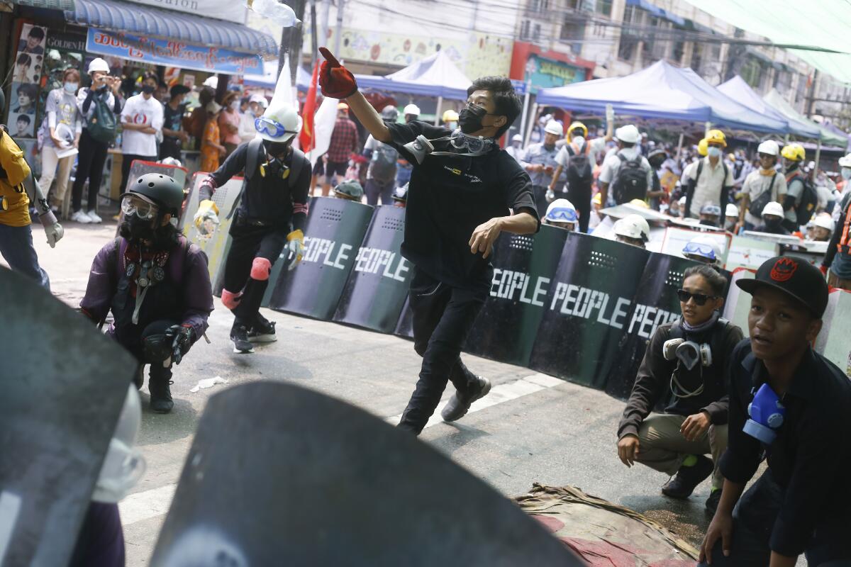 People in the streets wear protective gear and hold shields