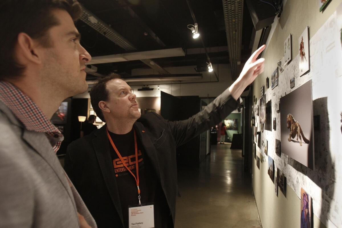 Assaf Horowitz, left, talks about his examples of concept art with Tim Flattery, chair of the entertainment design program at the Art Center College of Design, during its VIP Graduation Show Preview in Pasadena. Horowitz is hoping to land a full-time job based on the strength of his art before graduation.