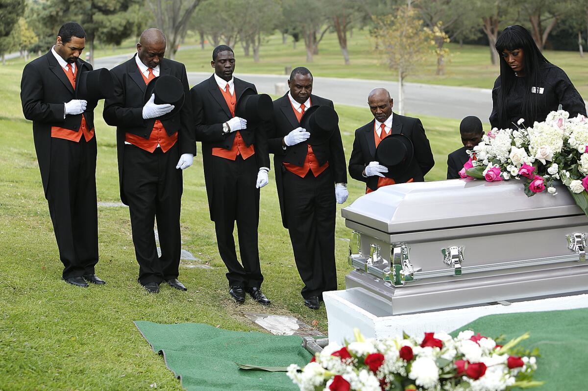 Professional pallbearers Derrick Royal, 38, Ricardo Beltran, 54, Jimmy Wilson, 34, Arthur Yarbrough, 45, Charles Lewis, 68, and Joe Jackson, 16, bow their heads along with funeral director Candy Boyd during Elnora Brown's burial at Rose Hills Memorial Park in Whittier.