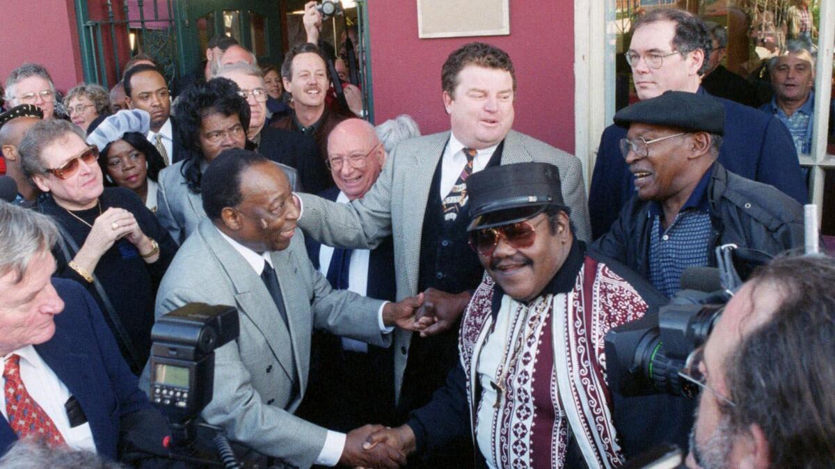 Fats Domino, center right, shakes hands with Dave Bartholomew in 1999 at the 50th anniversary observance of Domino's first recording session in New Orleans.