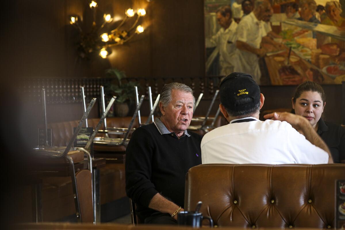 Norm Langer, left, owner of Langer's Delicatessen and Restaurant, holds a staff meeting Monday after closing dine-in service for at least two weeks in compliance with an order by Los Angeles Mayor Eric Garcetti aimed at limiting the spread of coronavirus.