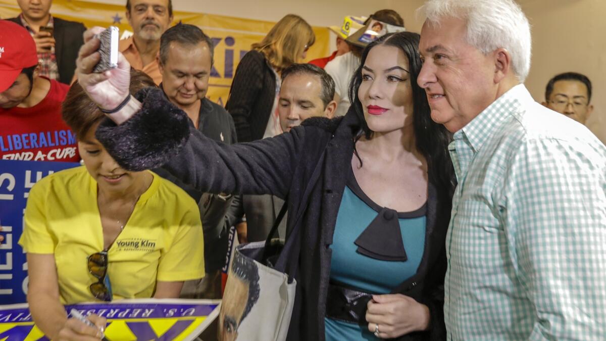 Republican candidate John Cox, right, takes a photo with a supporter during a campaign event with congressional candidate Young Kim, left.