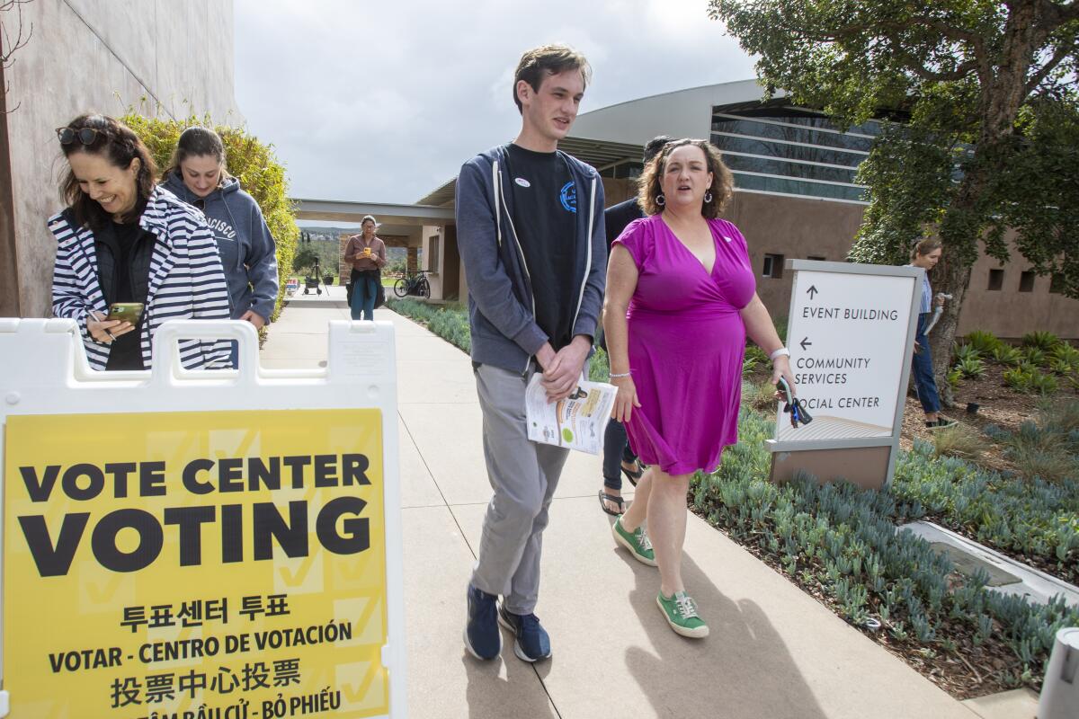 Rep. Katie Porter leaves with her son, Luke Hoffman, 18, who is a first-time voter, after casting their ballots.