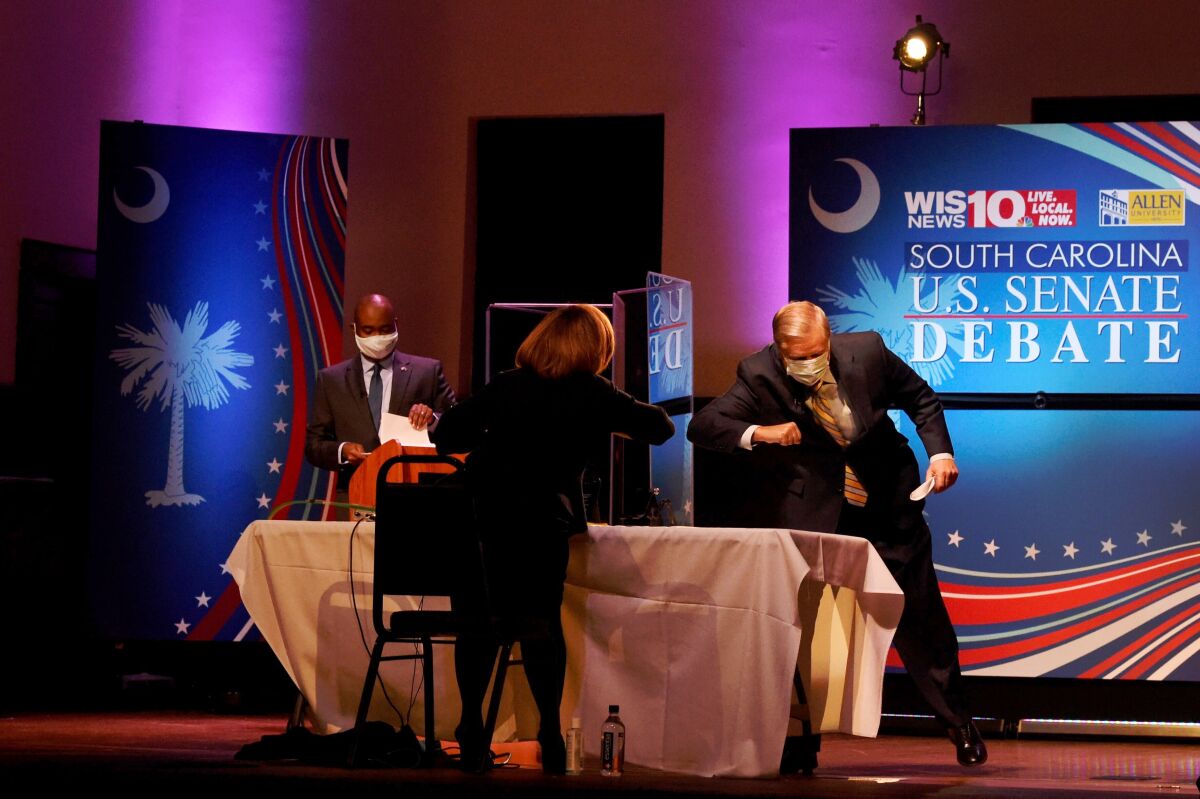 Sen. Lindsey Graham, right, gives moderator Judi Gatson an elbow bump after debating challenger Jaime Harrison.