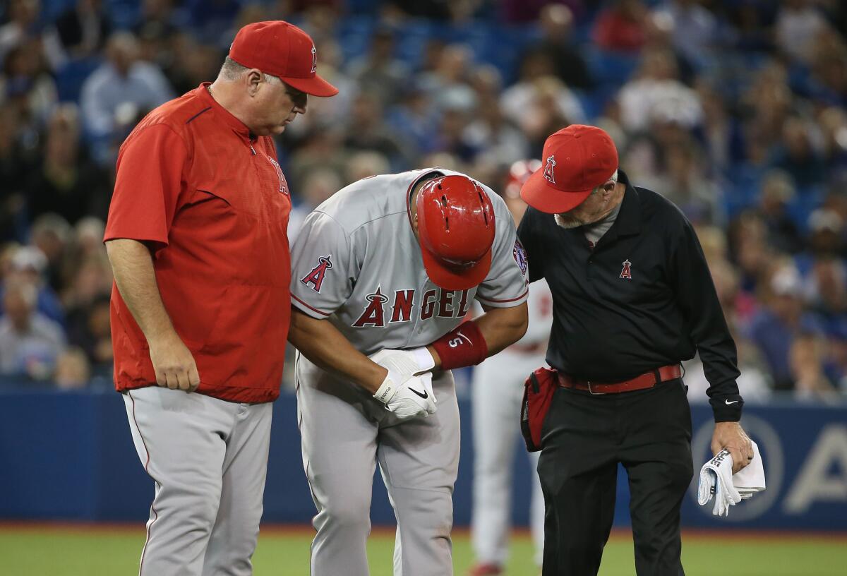 Manager Mike Scioscia, left, and the Angels trainer tend to Angels first baseman Albert Pujols after the slugger was hit on his left hand by a pitch.