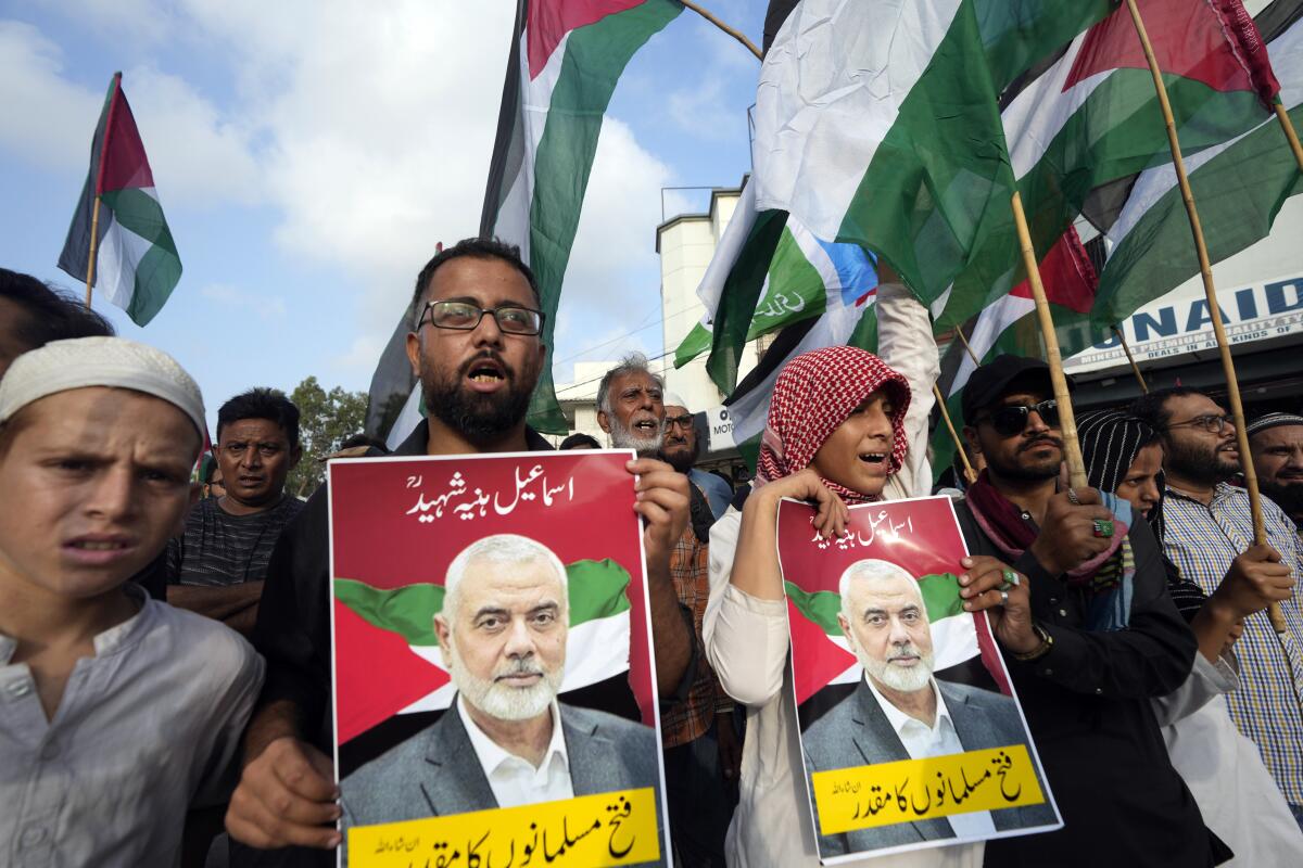 Supporters of Pakistani religious group 'Jamaat-e-Islami' hold posters with the portrait of Hamas leader Ismail Haniyeh 