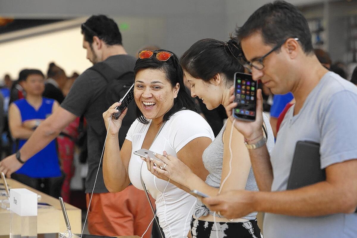 Erika Castillo, left, Cassidy Amador and Dan Unger check out the new iPhones at the Apple Store in Santa Monica. Supply shortages hampered first weekend sales totals for the iPhone 6 and 6 Plus.