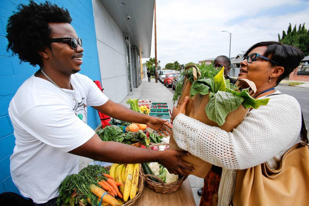 Dyane Pascal of Community Services Unlimited gives Karyn Williams a bag of produce outside St. John's Well Child and Family Center in South L.A.