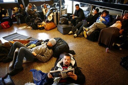 Adam Seymour, foreground, trying to fly from Seattle to Oakland, rests on the floor with other passengers on Dec. 22 at Seattle-Tacoma International Airport.