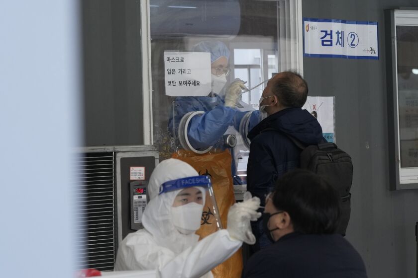 Medical workers take nasal samples from people at a makeshift coronavirus testing site in Seoul, South Korea, Tuesday, Dec, 14, 2021. (AP Photo/Ahn Young-joon)