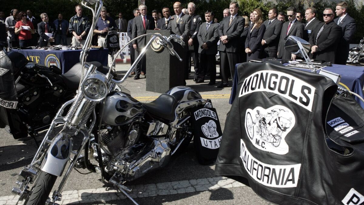 Law enforcement officials announce the arrests of dozens of members of the Mongols motorcycle club in 2008. A jury found the club guilty in a current racketeering case. Federal prosecutors want the club to forfeit the trademark it has on its insignia, which is seen on the jacket.