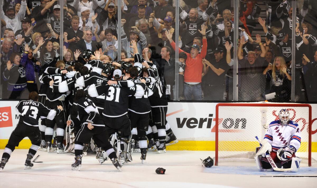 Kings players celebrate winning the Stanley Cup as Rangers goalie Henrik Lundqvist looks on.