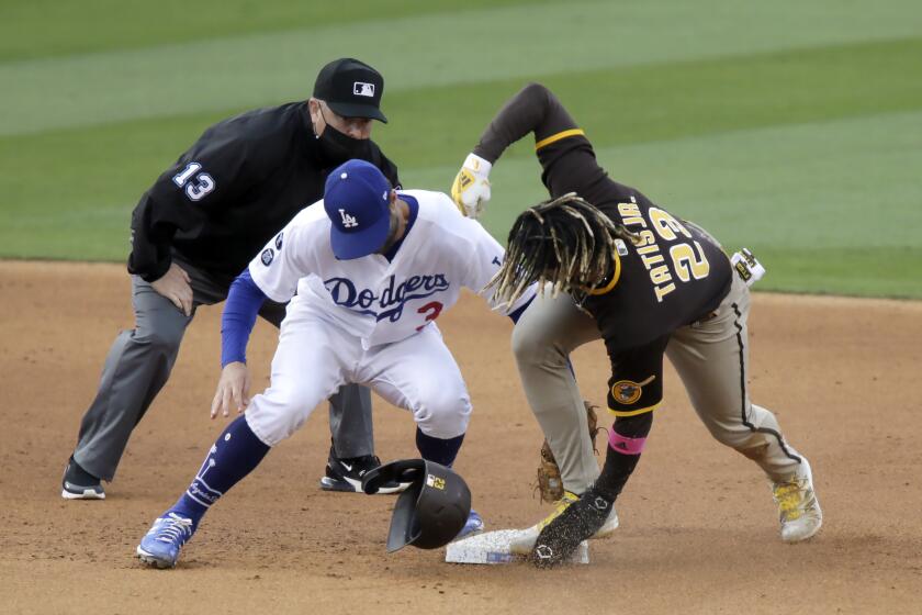 San Diego Padres' Fernando Tatis Jr., right, steals second as Los Angeles Dodgers second baseman Chris Taylor applies the late tag with umpire Todd Tichenor, left, watching during the sixth inning of a baseball game in Los Angeles, Sunday, April 25, 2021. (AP Photo/Alex Gallardo)