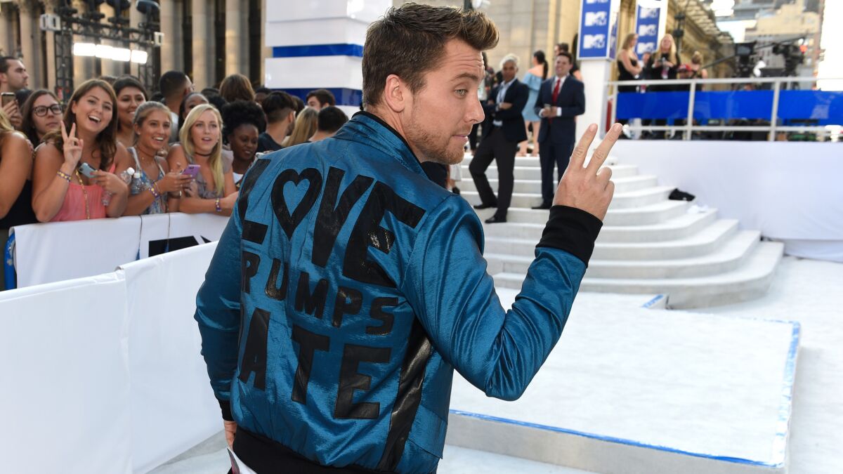 Lance Bass wears a jacket by Rey Ortiz with the slogan "Love Trumps Hate" across the back.