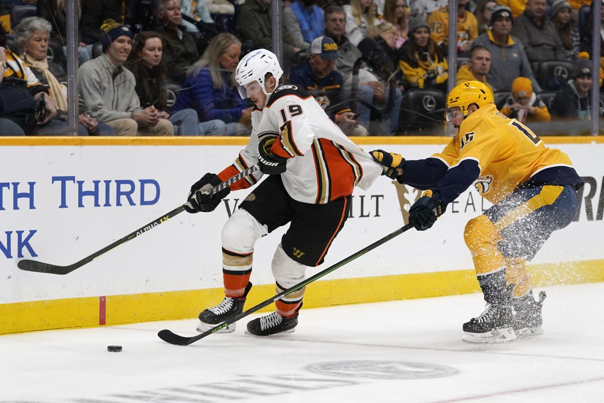 Nashville Predators defenseman Alexandre Carrier hangs onto the jersey of Ducks right wing Troy Terry.