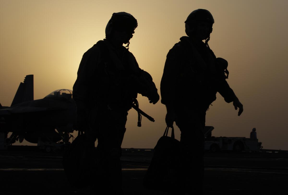 Pilots walk at sunset on the flight deck of the U.S. Navy aircraft carrier USS George H.W. Bush.