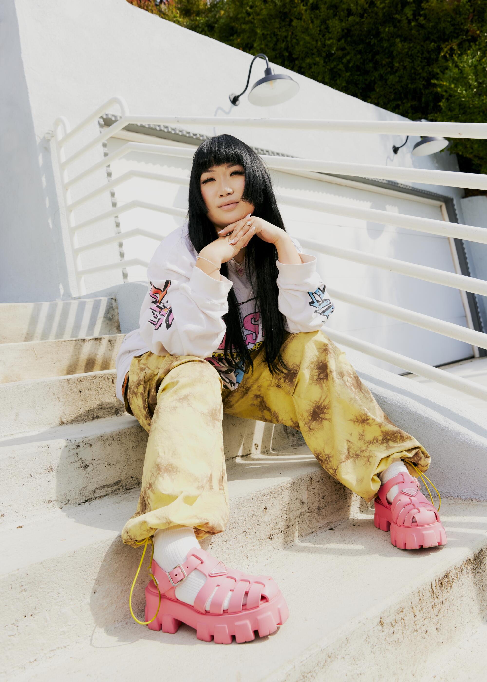 Stylist Jess Mori sitting on outdoor steps, wearing pink shoes.