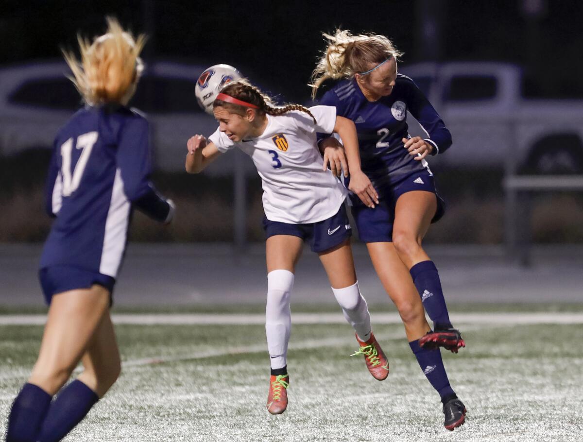 Marina's Riley Crosby (3) heads the ball contested by Newport Harbor's Laine Briggs during a Wave League girls' soccer game.