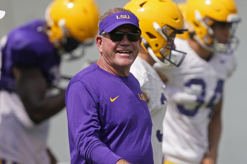 LSU head coach Brian Kelly smiles as he walks across the field during NCAA college football practice.