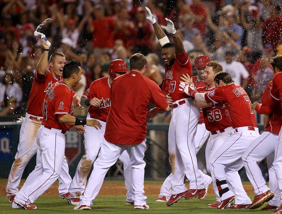 Howie Kendrick, center, is rushed by his teammates after hitting a game-winning sacrifice fly to score Albert Pujols and give the Angels a 4-3 win over the Athletics in 10 innings.