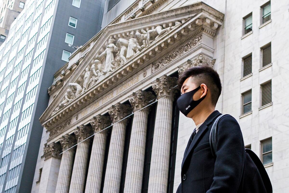 A man wearing a mask walks past the New York Stock Exchange earlier this week. World financial markets are reacting to the coronavirus outbreak.