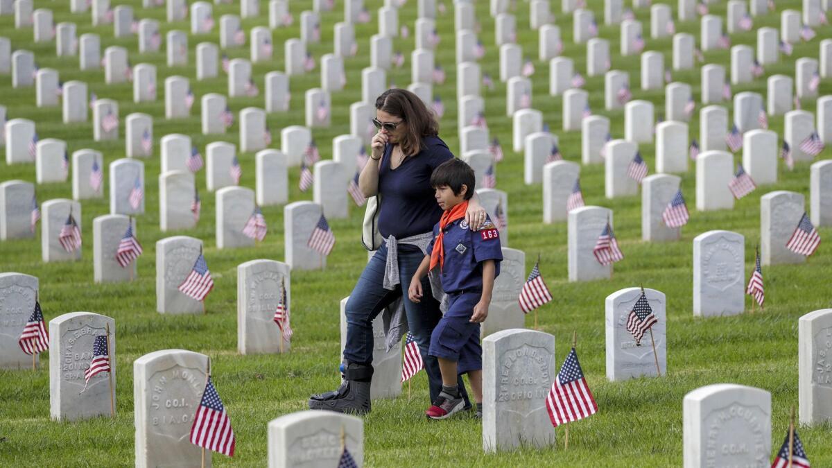 Jen Duffy, with her 6-year-old son Xavier Duffy, walks through veteran's graves at Los Angeles National Cemetery after placing a flag and paying her respects. More than 10,000 Scouts place 90,000 flags on the graves of service members to honor their sacrifices on Memorial Day.