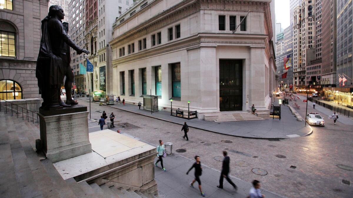 People walk to work on Wall Street in New York beneath a statue of George Washington in 2014.