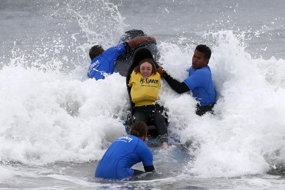 Emily Rowley is taken out to ride a "chair board" on Friday morning in Huntington Beach.
