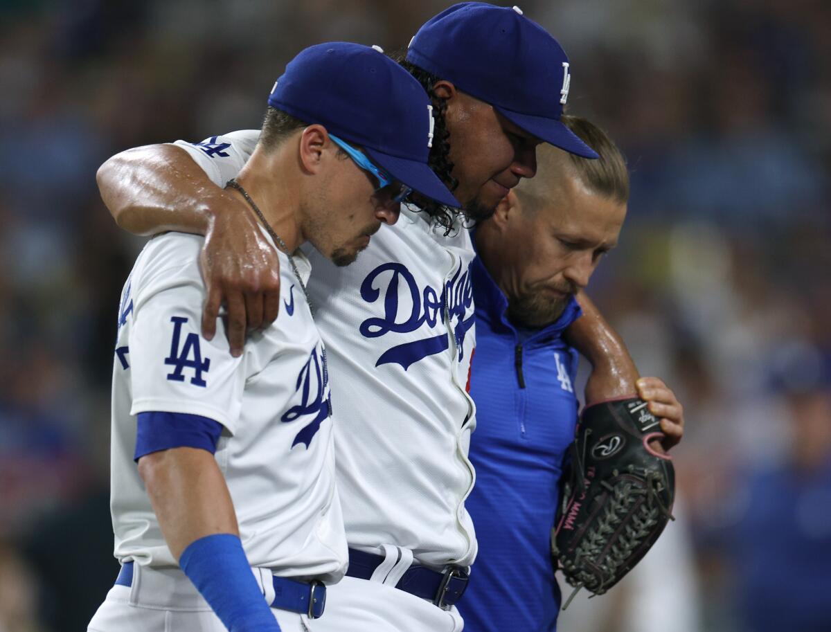 Brusdar Graterol is helped off the field by Kiké Hernández and medical staff during the sixth inning.