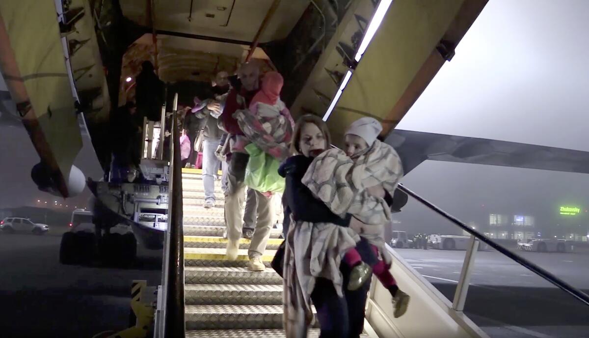 In a photo taken from video, Russian officials carry children from a plane Nov. 18 at Zhukovsky International Airport outside Moscow.